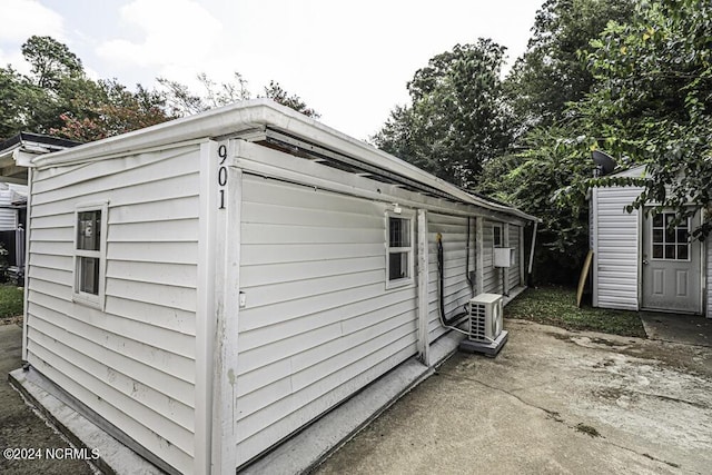 view of side of home with ac unit, an outdoor structure, and a patio