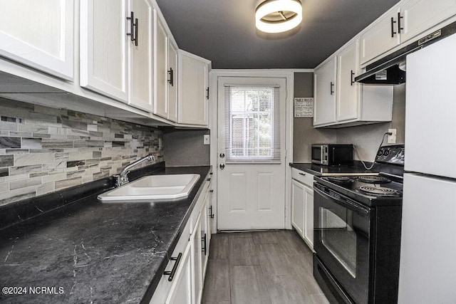 kitchen featuring dark countertops, freestanding refrigerator, black electric range, white cabinetry, and a sink