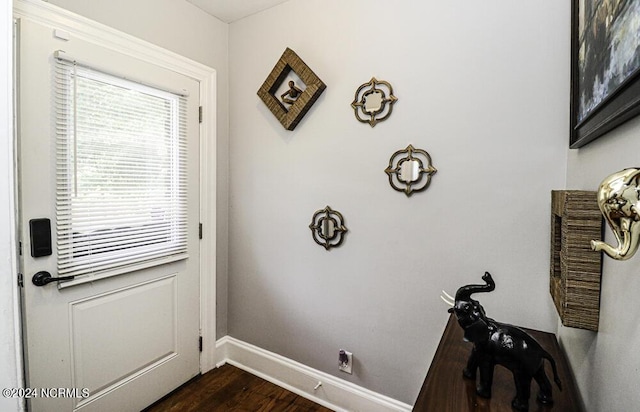 doorway featuring dark wood-style flooring and baseboards