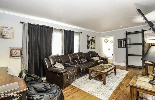 living room featuring baseboards, a barn door, wood finished floors, and crown molding