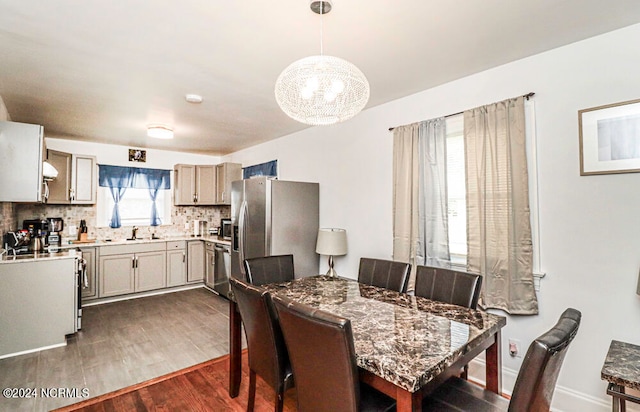 dining space featuring an inviting chandelier, sink, and dark hardwood / wood-style flooring