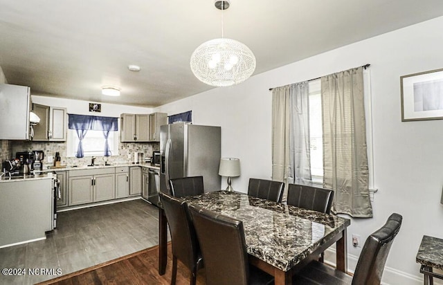 dining area with dark wood-style flooring, baseboards, and an inviting chandelier