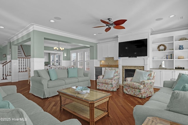 living room with ornamental molding, ceiling fan with notable chandelier, and hardwood / wood-style floors