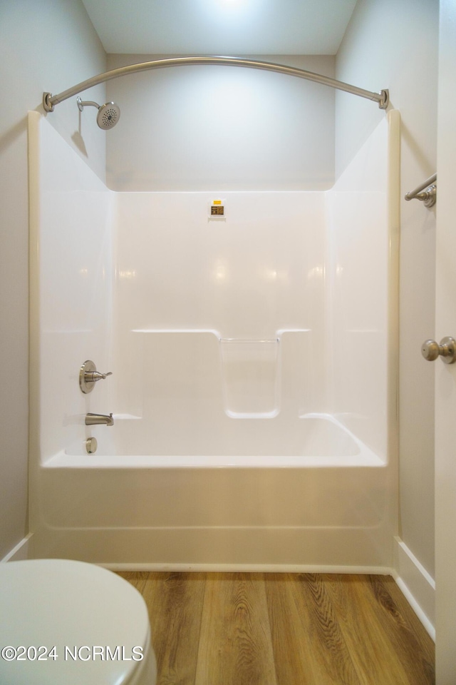 bathroom featuring shower / tub combination, wood-type flooring, and toilet