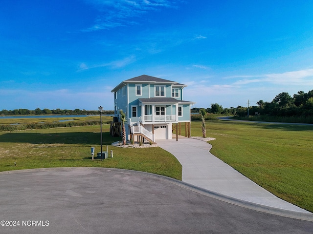 coastal home featuring a garage, a front yard, driveway, and stairs