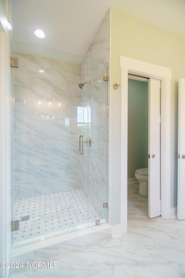 bathroom with toilet, a shower with shower door, and lofted ceiling