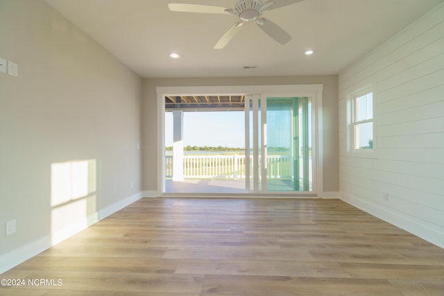 empty room with a wealth of natural light, ceiling fan, and light wood-type flooring