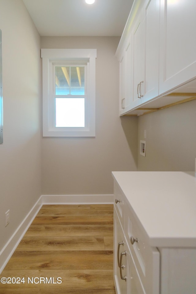 clothes washing area featuring washer hookup, light hardwood / wood-style flooring, and cabinets