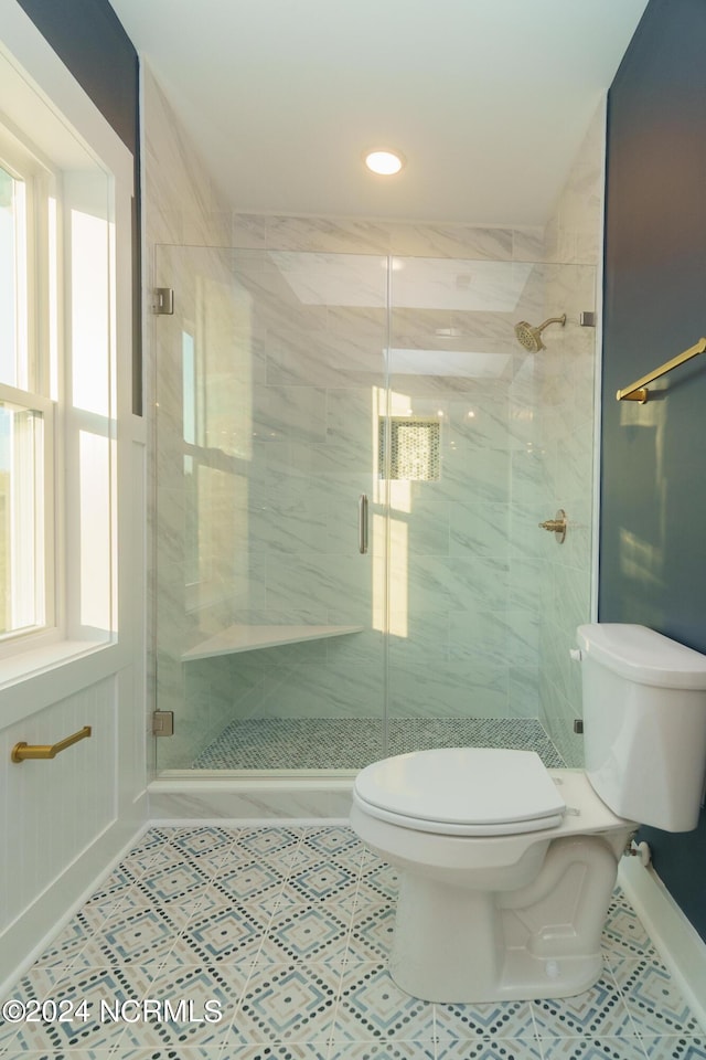 bathroom featuring toilet, a shower with shower door, and tile patterned flooring