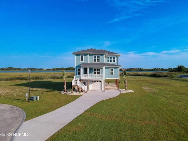 view of front of home with a garage, a water view, and a front lawn