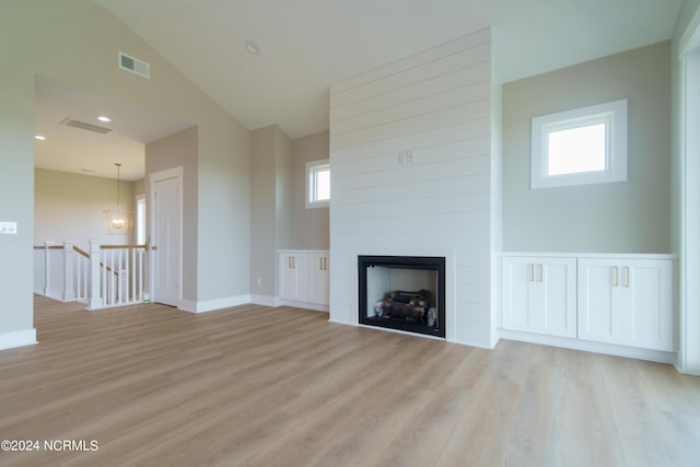 unfurnished living room with a large fireplace, a wealth of natural light, and light hardwood / wood-style floors