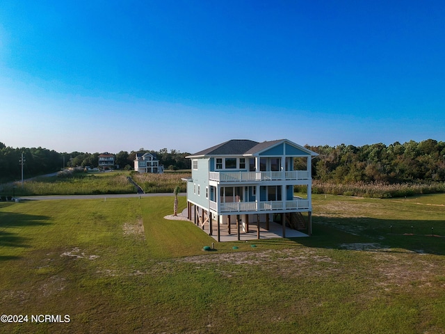 rear view of house with a lawn and a balcony