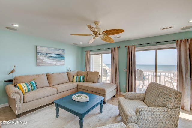 living room featuring ceiling fan, light tile patterned floors, and a water view