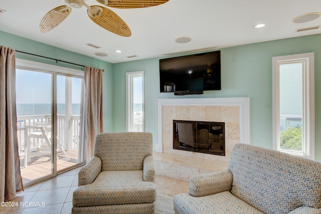 living room featuring ceiling fan, a premium fireplace, light tile patterned flooring, and a healthy amount of sunlight