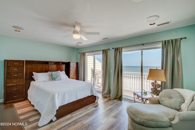 bedroom featuring light wood-type flooring, a water view, ceiling fan, and access to exterior