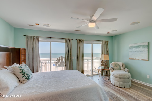 bedroom with ceiling fan, light hardwood / wood-style floors, access to exterior, and a water view