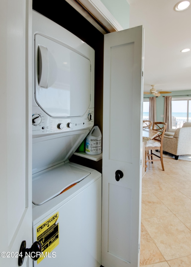 laundry room with stacked washer and clothes dryer, light tile patterned flooring, and ceiling fan