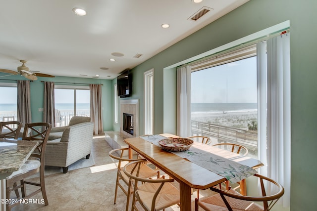 tiled dining room featuring a water view and ceiling fan