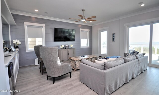 living room with light hardwood / wood-style flooring, ceiling fan, and crown molding