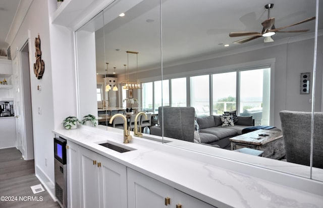 kitchen with white cabinets, light stone countertops, dark hardwood / wood-style flooring, crown molding, and sink