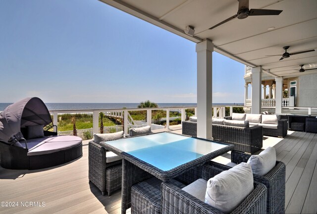 deck with a water view, outdoor lounge area, and ceiling fan