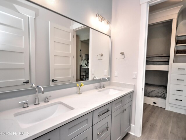 bathroom with double vanity, wood finished floors, and a sink