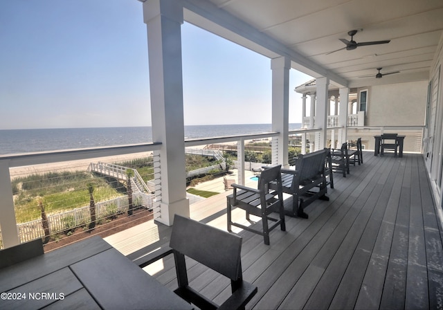 wooden deck featuring a view of the beach, a water view, and ceiling fan