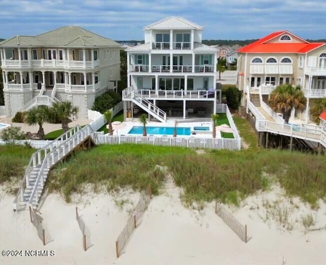 back of property with a fenced in pool, a patio area, a balcony, a fenced backyard, and stairs