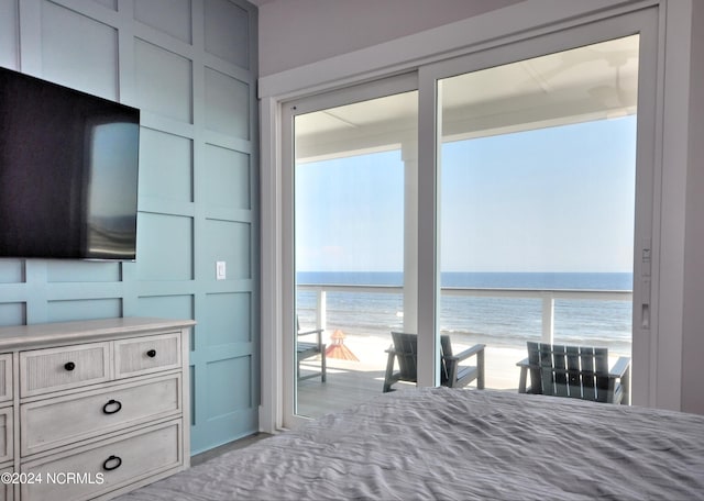 unfurnished bedroom with a view of the beach, multiple windows, a decorative wall, and a water view