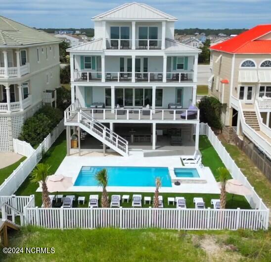 rear view of house with a balcony, a patio area, and a fenced in pool