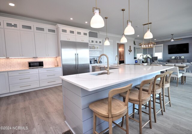 kitchen with white cabinets, a large island, stainless steel appliances, and hanging light fixtures