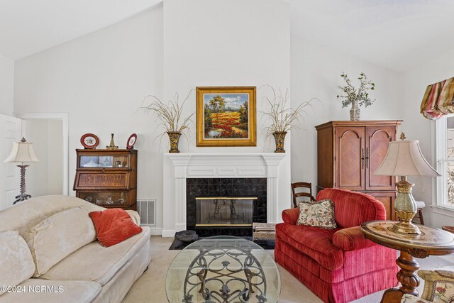 living room featuring light colored carpet, high vaulted ceiling, and a tile fireplace