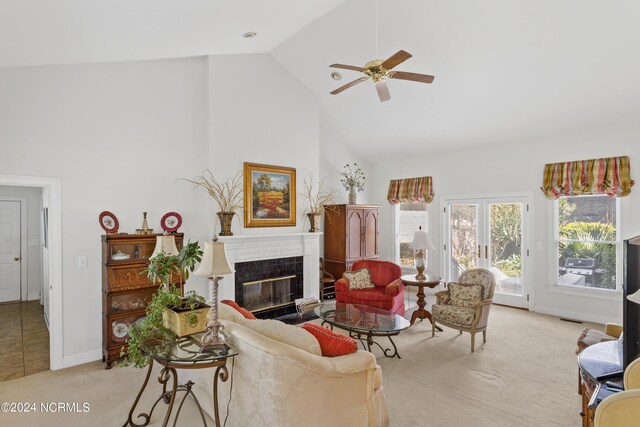 carpeted living room featuring high vaulted ceiling, ceiling fan, and a tile fireplace