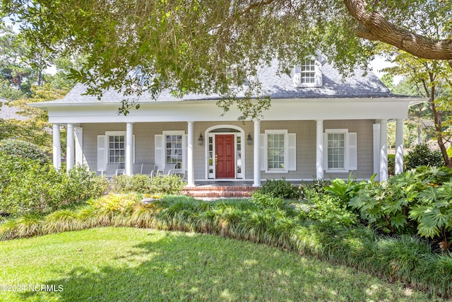 view of front of property with covered porch, a shingled roof, and a front lawn