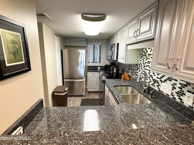 kitchen featuring a textured ceiling, backsplash, sink, appliances with stainless steel finishes, and hardwood / wood-style flooring