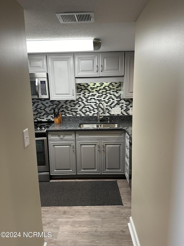 kitchen featuring visible vents, appliances with stainless steel finishes, gray cabinets, and a sink