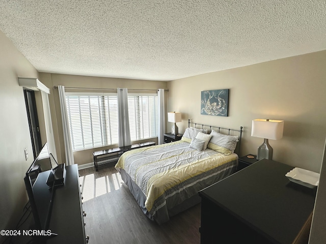 bedroom featuring a textured ceiling and dark hardwood / wood-style floors