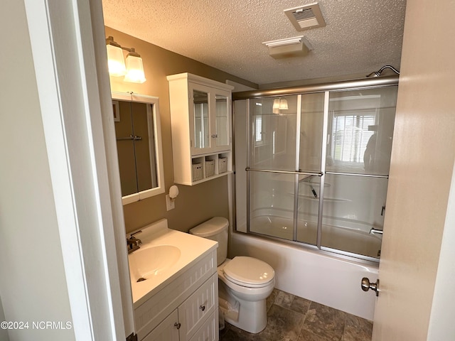 full bathroom featuring a textured ceiling, vanity, toilet, and combined bath / shower with glass door