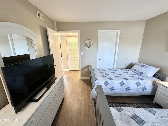 bedroom with visible vents, baseboards, and wood finished floors