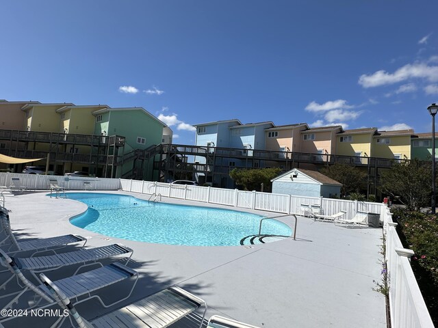 community pool featuring a patio area, fence, and a residential view