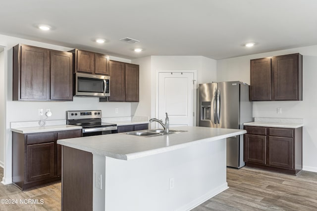 kitchen with an island with sink, appliances with stainless steel finishes, sink, and dark brown cabinets