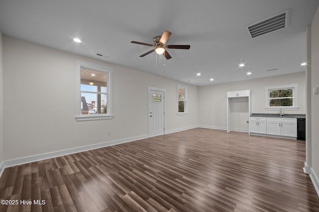 unfurnished living room with dark hardwood / wood-style flooring, ceiling fan, and sink