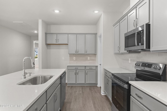 kitchen featuring appliances with stainless steel finishes, gray cabinets, light hardwood / wood-style flooring, and sink