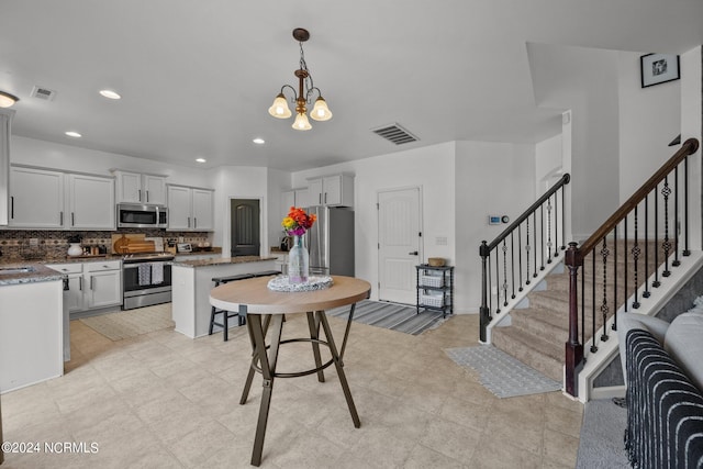 kitchen featuring dark stone counters, a chandelier, stainless steel appliances, a center island, and hanging light fixtures