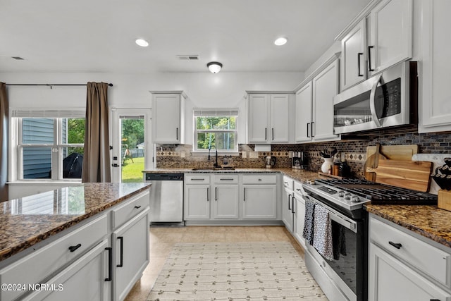 kitchen featuring dark stone counters, stainless steel appliances, visible vents, and decorative backsplash