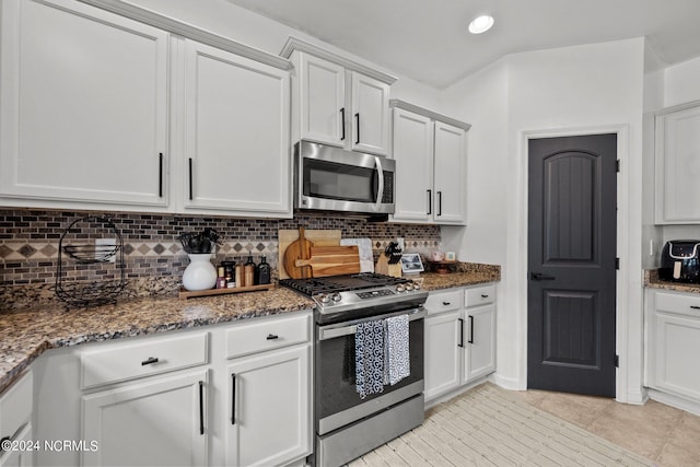 kitchen featuring appliances with stainless steel finishes, dark stone countertops, backsplash, and white cabinets