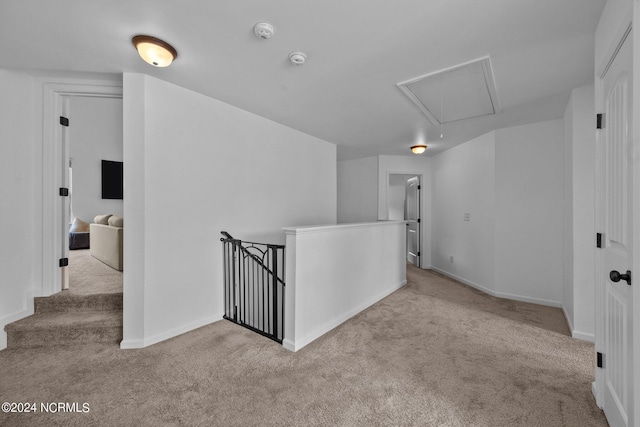 hallway featuring carpet, attic access, baseboards, and an upstairs landing