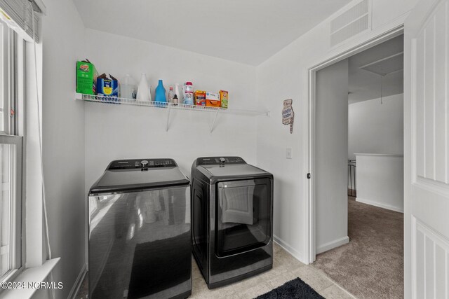 clothes washing area with washer and clothes dryer and light colored carpet