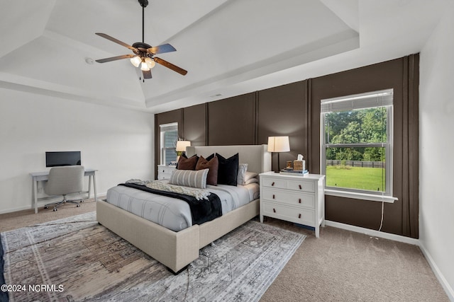 carpeted bedroom with a tray ceiling and ceiling fan