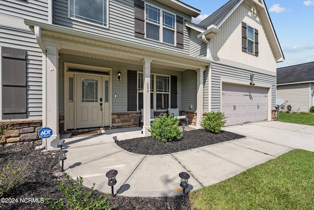 view of front of house featuring a garage, stone siding, a porch, and concrete driveway